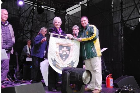 Olga Swanepoel oorhandig die skoolwapen van Bekker Landbou Hoërskool, wat sy spesiaal gekwilt het, aan die skoolhoof tydens die skool se 80-jarige feesvieringe